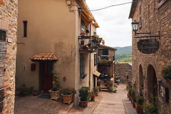 Quiet stone street in Allerona with balconies, plants in terracotta pots and an osteria sign